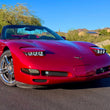 Load image into Gallery viewer, A red C5 Corvette convertible with knightdrivetv sleepy eye tripleds headlights and bezels.  Sports car parked outdoors on a paved surface with desert vegetation, rocks, and a blue sky in the background.
